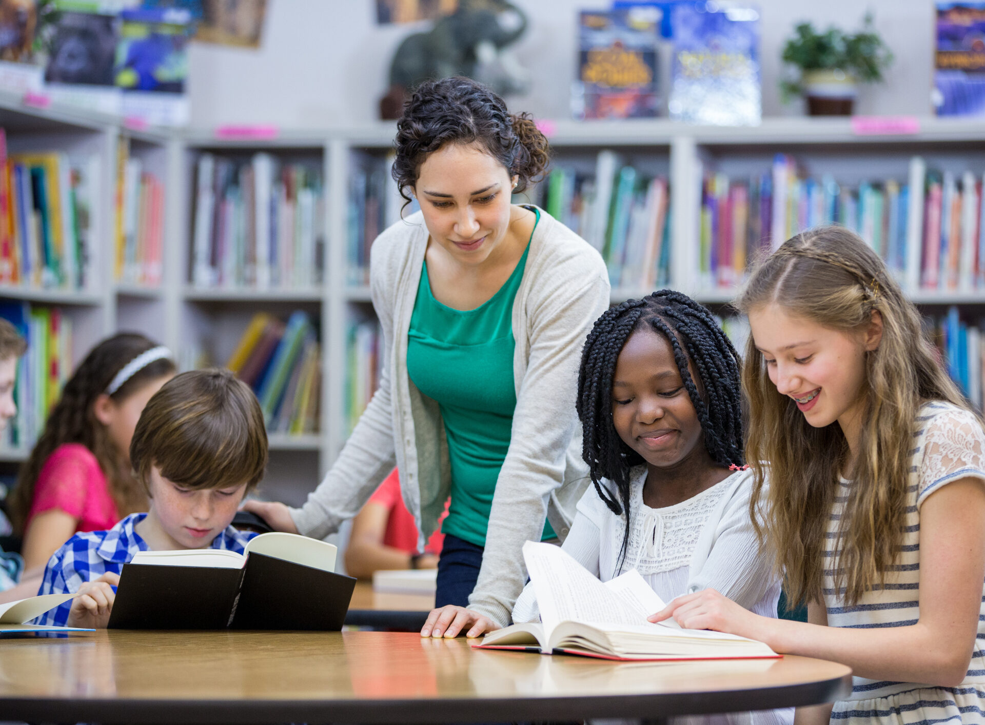 Elementary students working with teacher in library