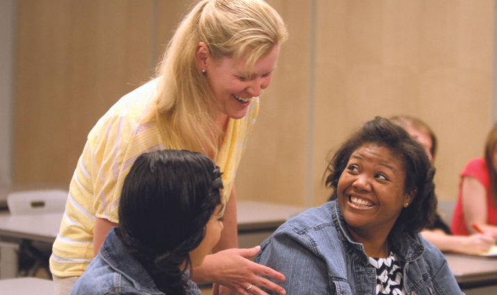 professor leaning over women talking