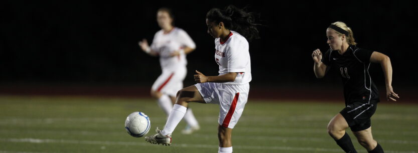 women's soccer player kicking the ball