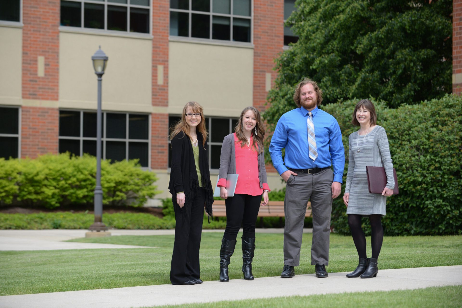 Adult student group posing on campus, outdoors, professional