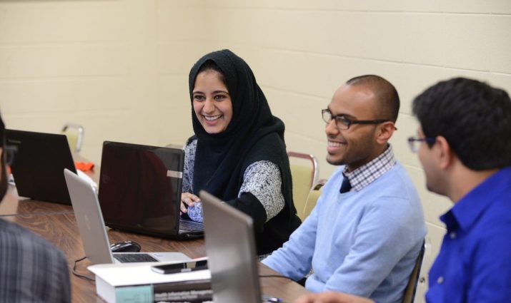 Students on laptops in classroom, adults, diversity