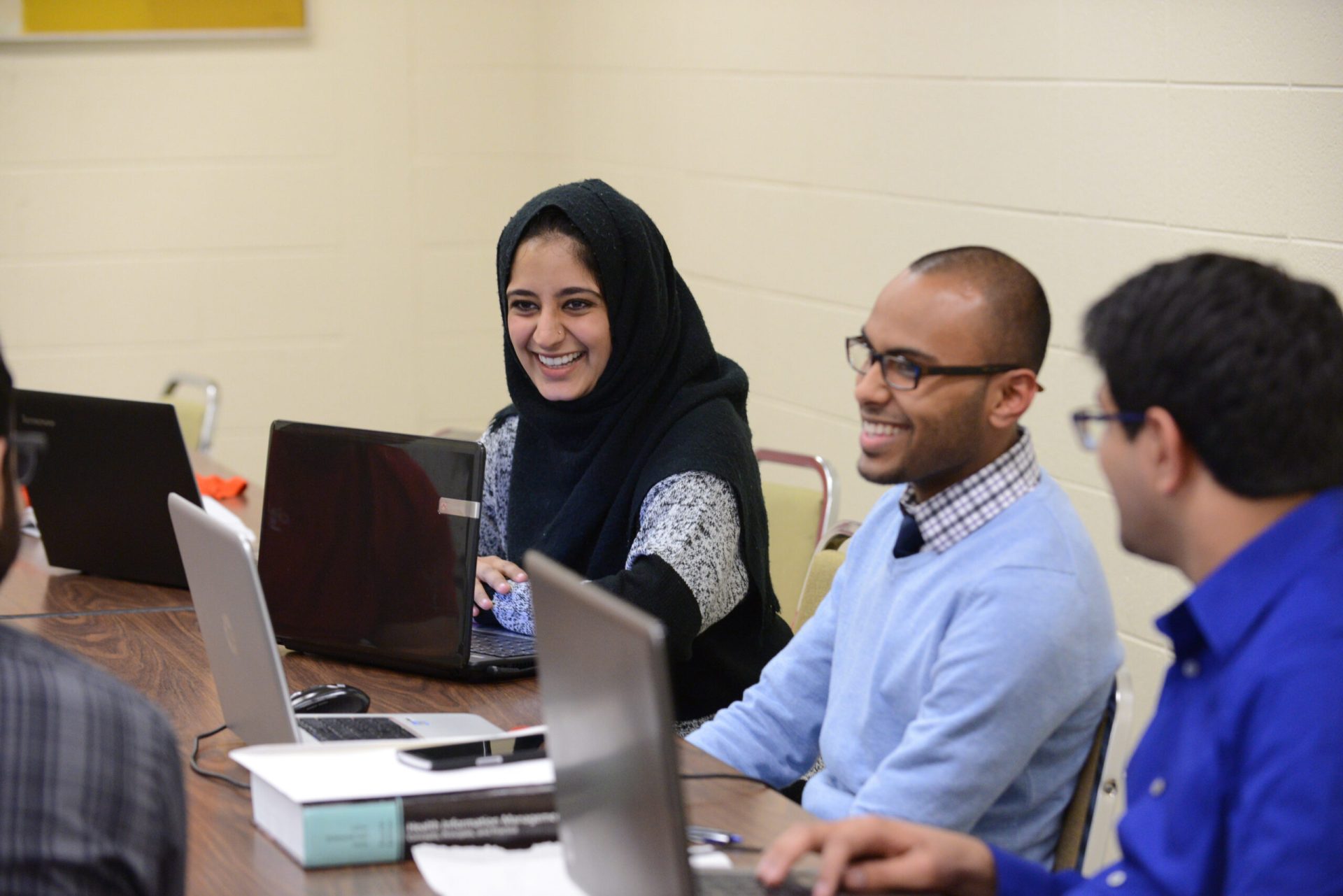 Students on laptops in classroom, adults, diversity