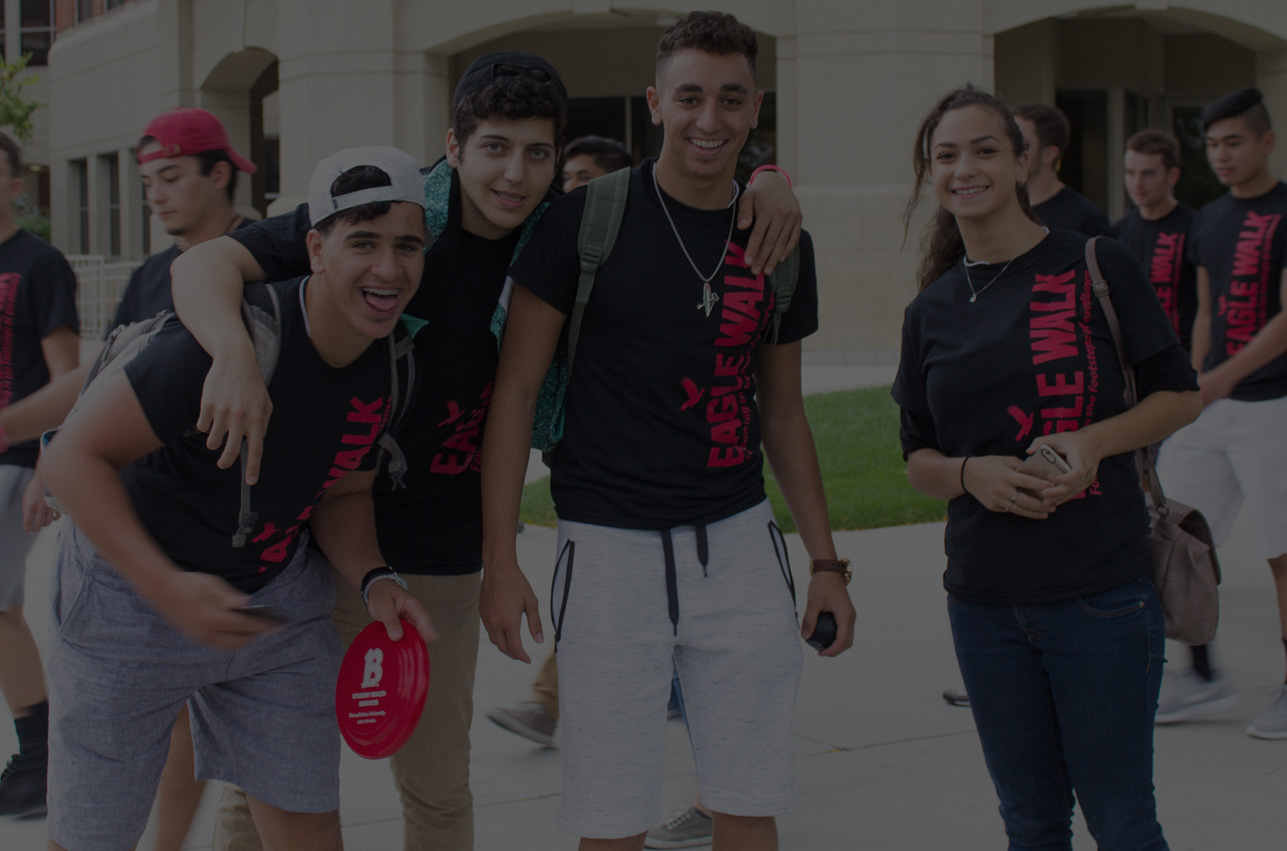 Group of students smiling together on the quad; image has black overlay