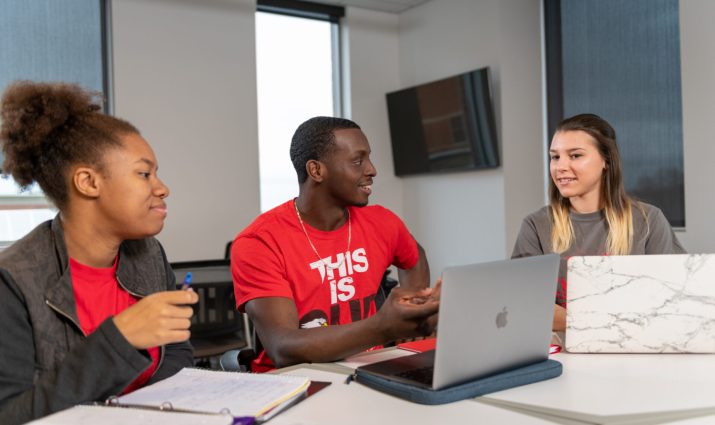 Students with laptops/books seated in a classroom