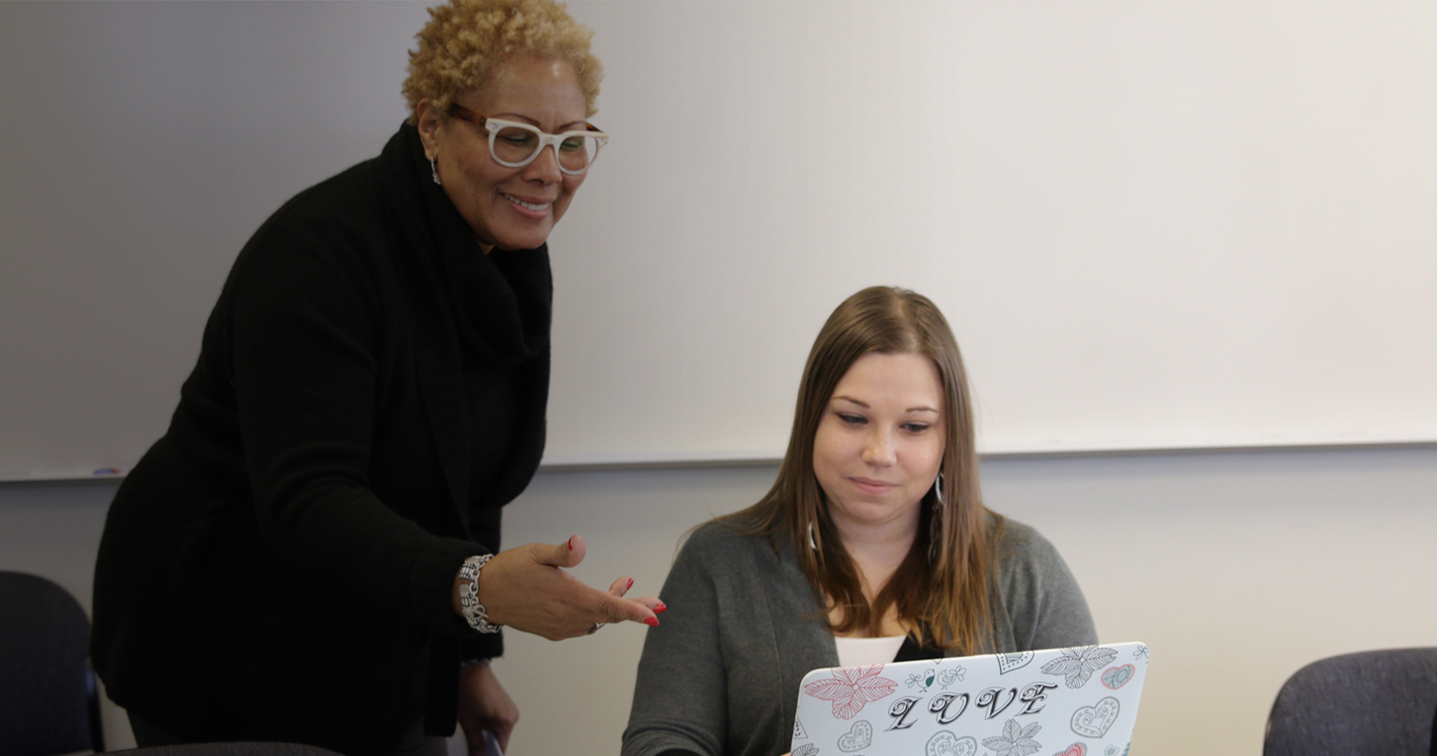 Female faculty member helping a student on her computer