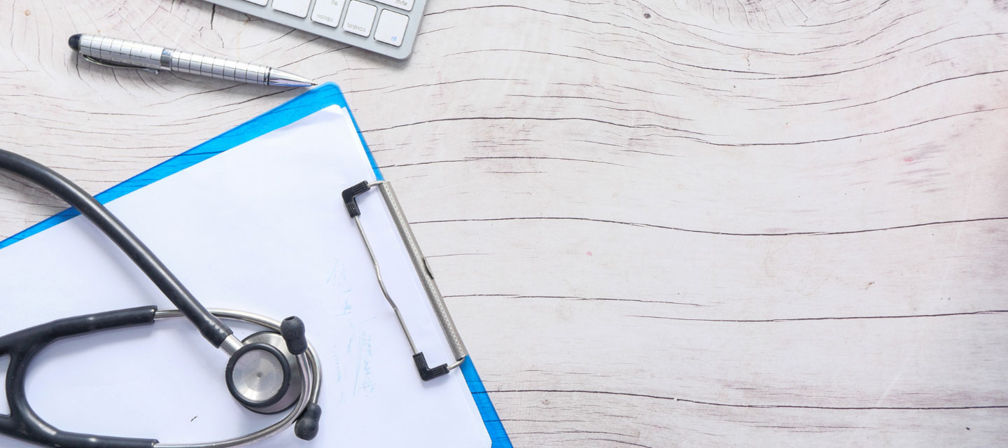 image of clipboard, stethoscope, pen and keyboard on a wooden desk; pre-physician assistant