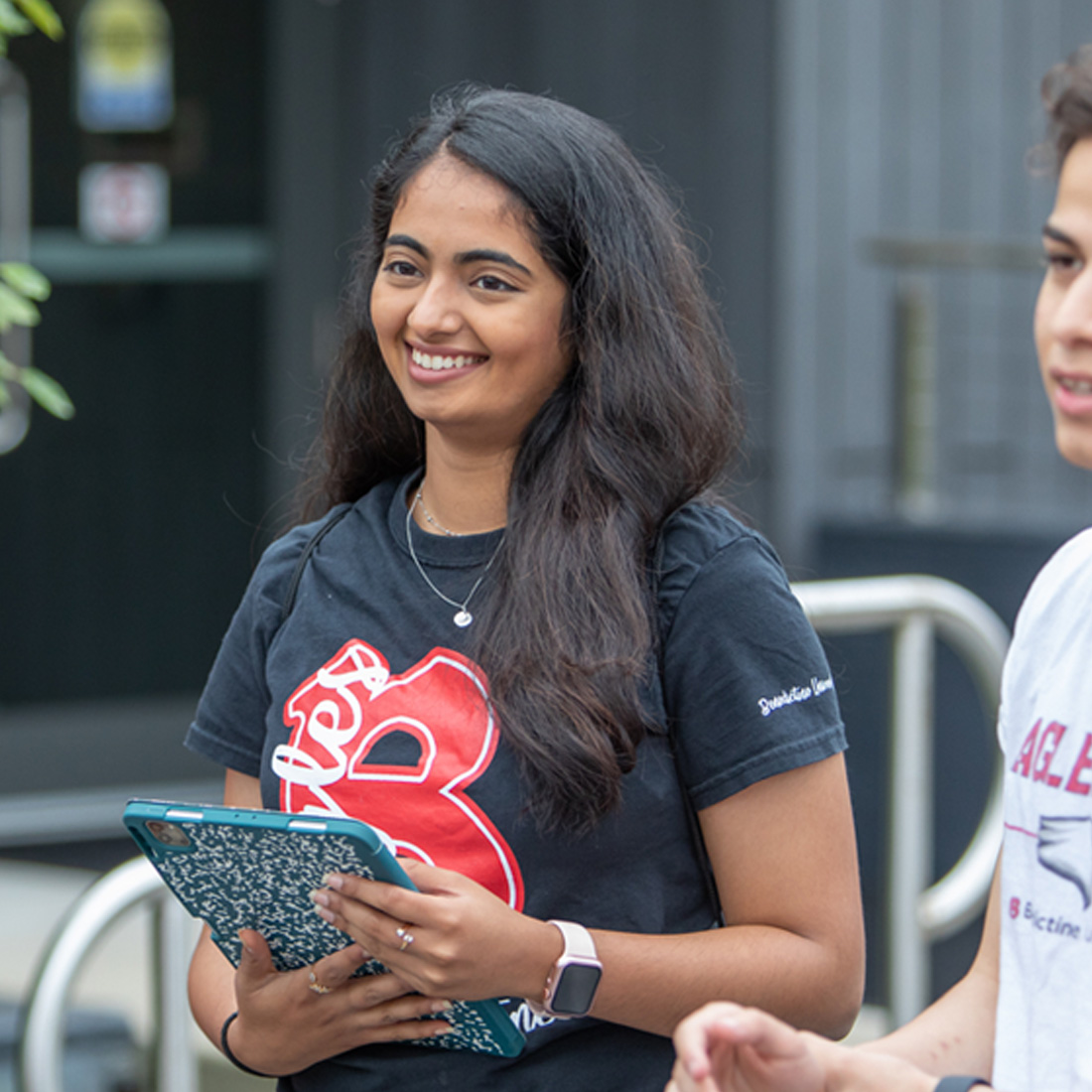 female student with iPad smiling with other students; financial aid