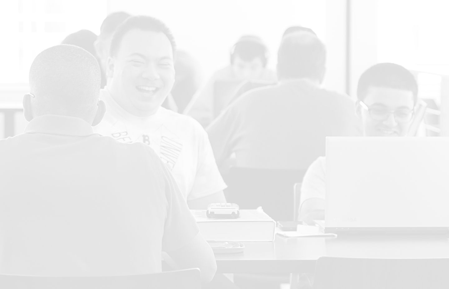 Male student laughing next to male student on a laptop; financial aid background