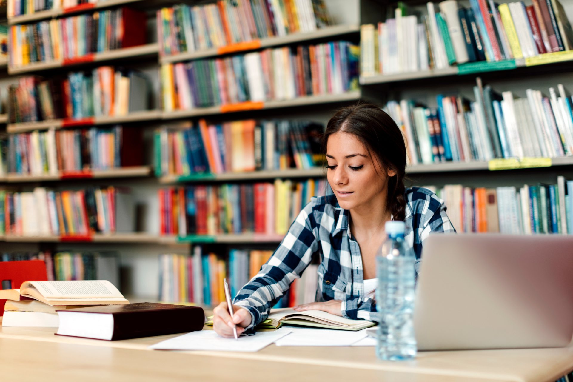 woman writing at desk in library; psychology