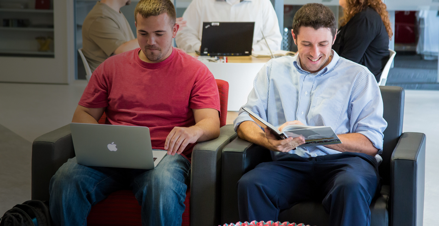 Older male students looking at a laptop and catalog; degree and transfer students