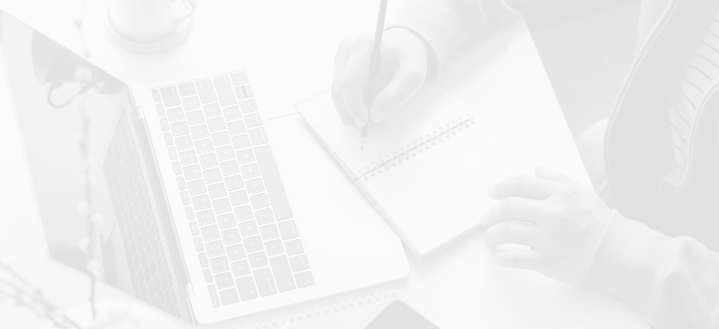 overhead view of hands writing in a notebook with a computer on table, image has a white overlay