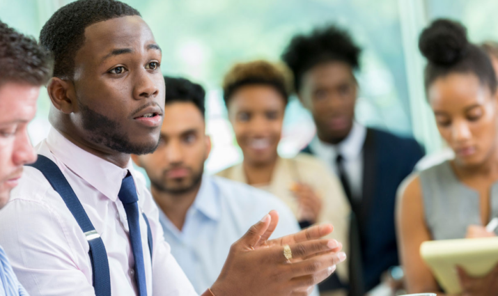 group of adult students in classroom setting, male student is speaking to group; Business administration