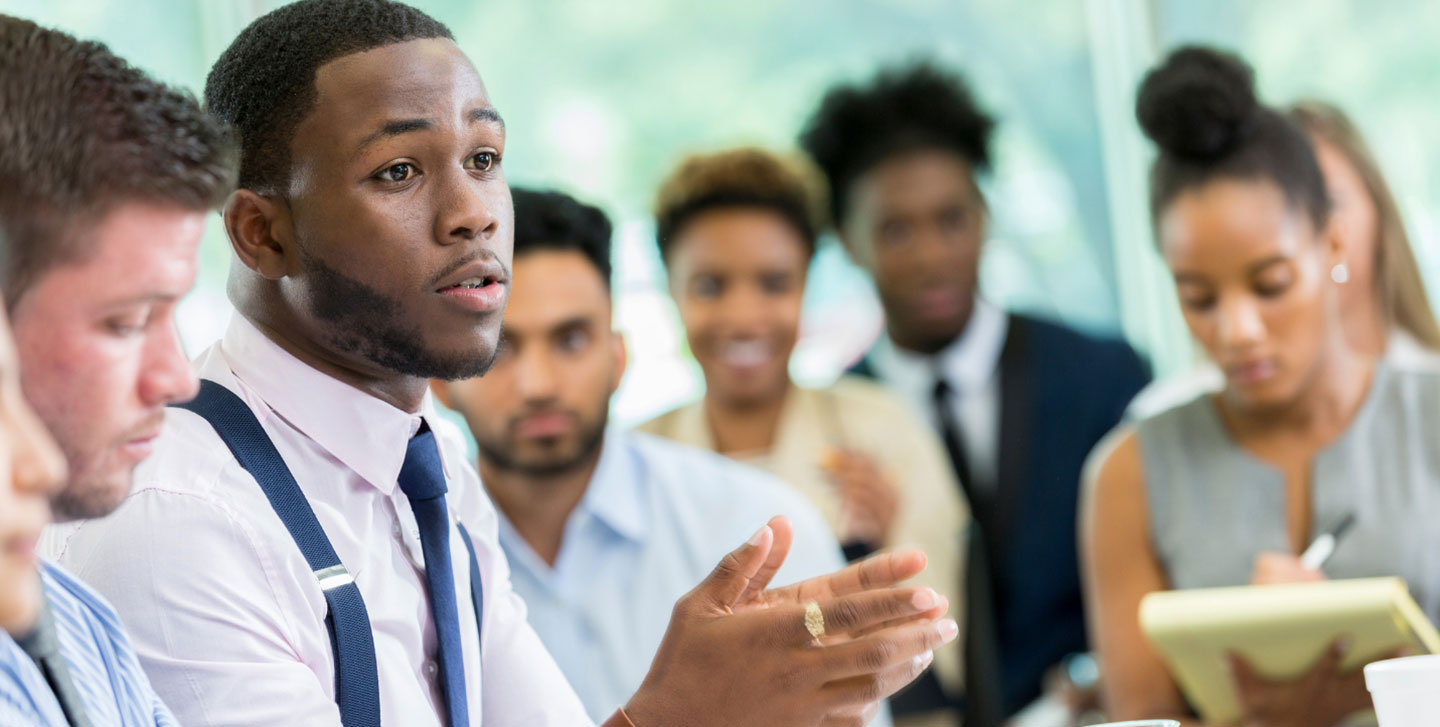 group of adult students in classroom setting, male student is speaking to group; Business administration