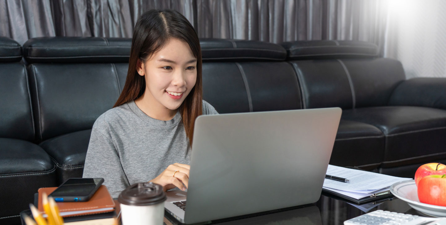 female student sitting on couch working on laptop; gender studies minor