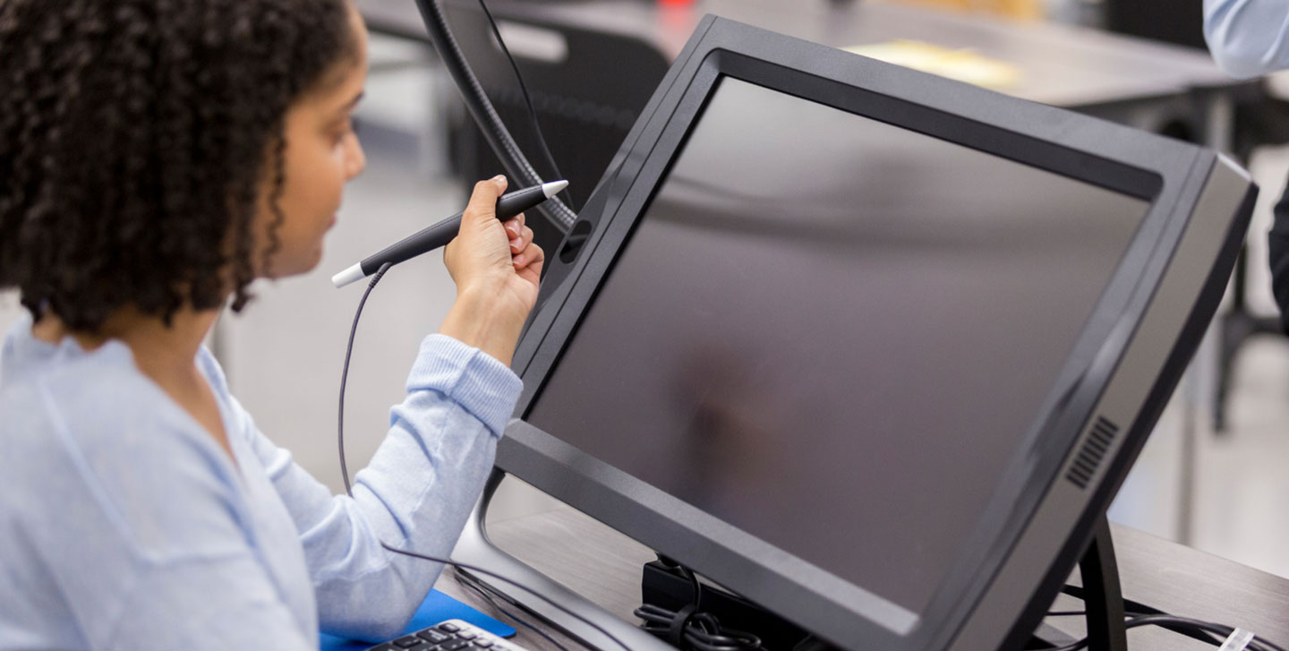female student holding pen used to write on a computer screen; graphic arts and design