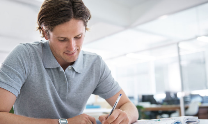 male student writing at desk; International Business and Economics program