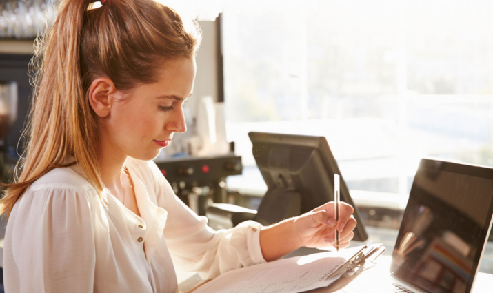Female student writing on a clipboard ; management program