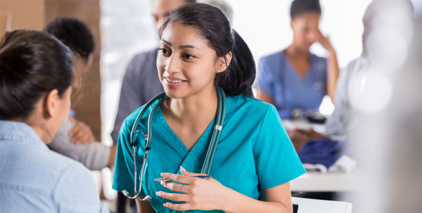 female medical student with stethoscope around her neck speaking to colleague; master of public health program