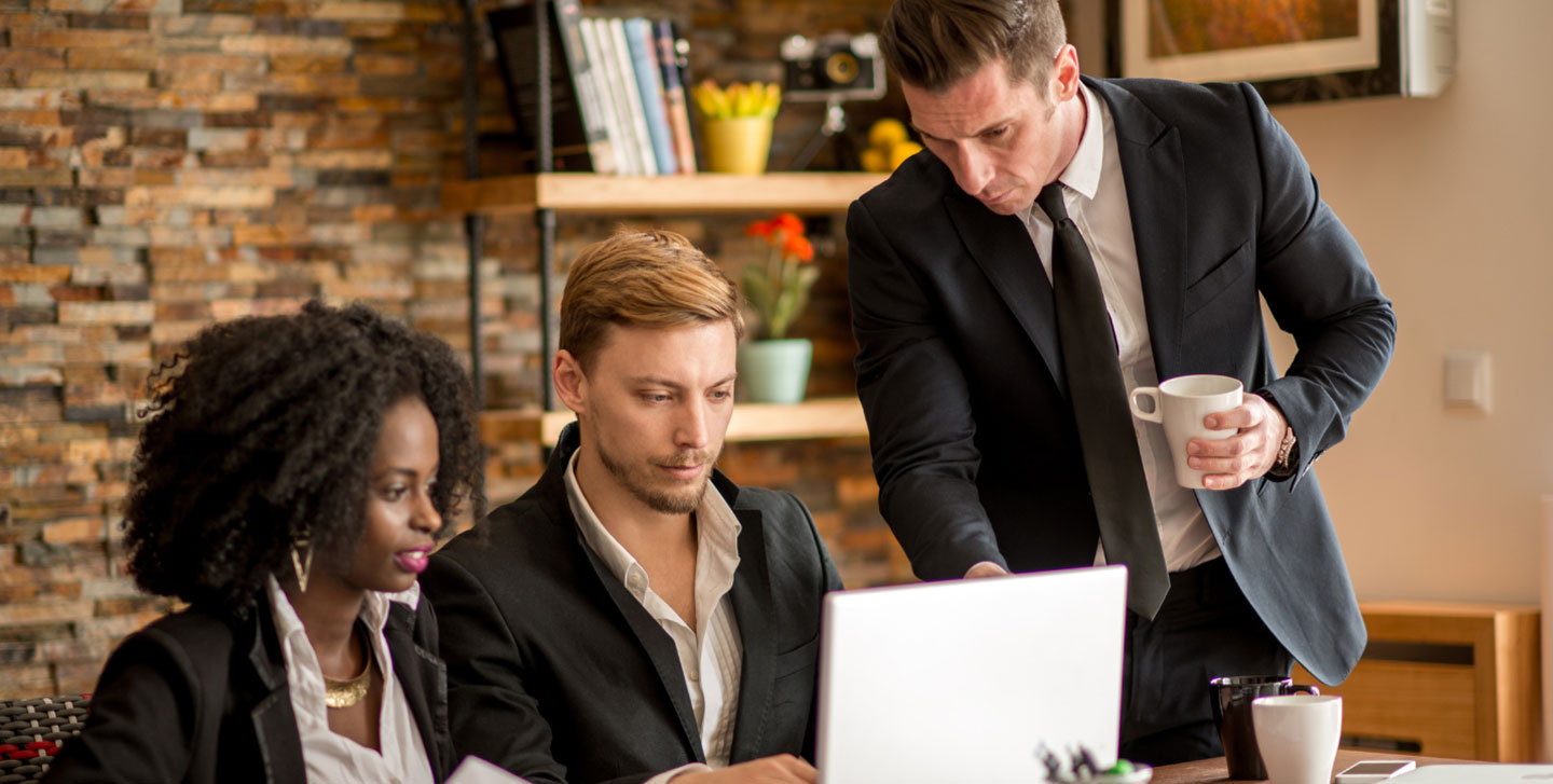 older professionals looking at a laptop. Management and Organizational Behavior MS program