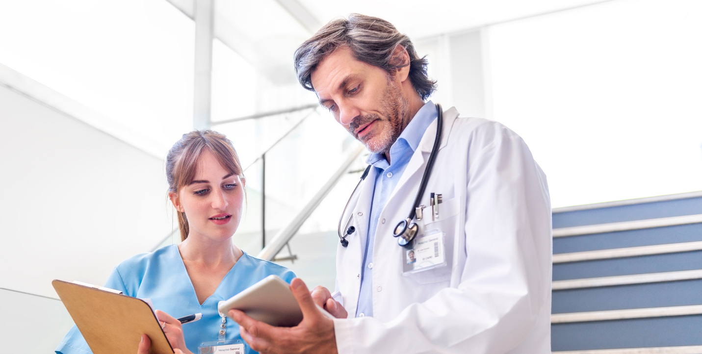 physician looking at notepad while resident copies information; medical humanities minor