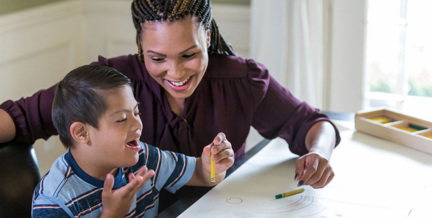 teacher helping autistic child with his coloring; special education