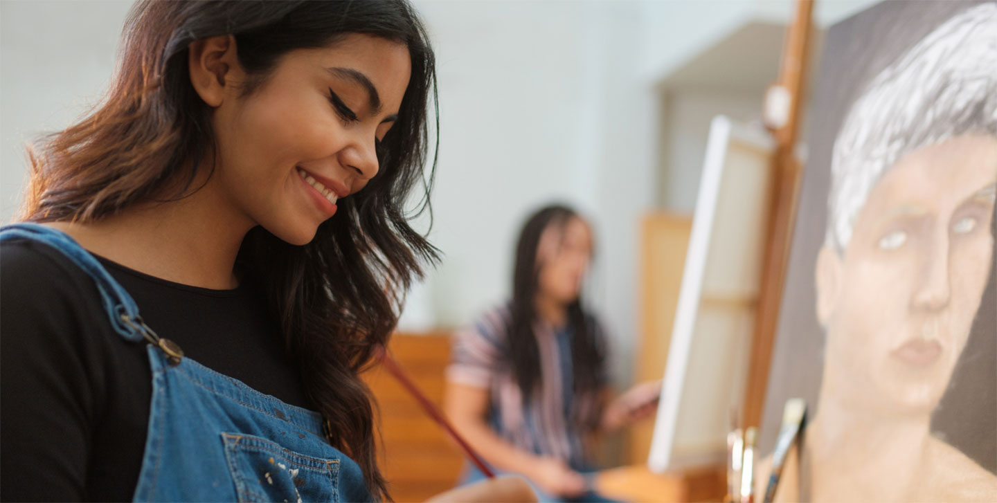 female art student smiling while at her canvas art project; studio art