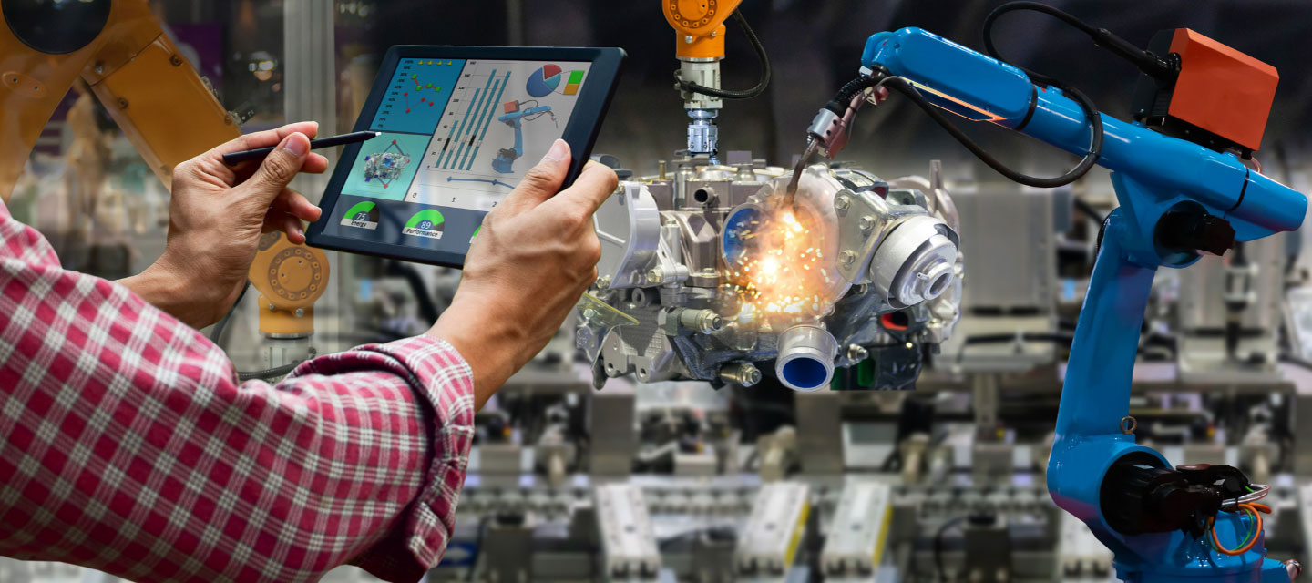 handing holding up and iPad with instructions for machinery in the background; engineering science