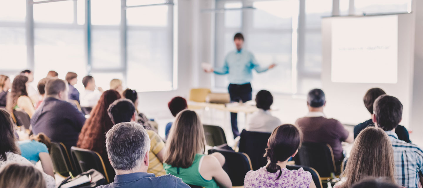 male giving a speech in front of an audience; master of public health
