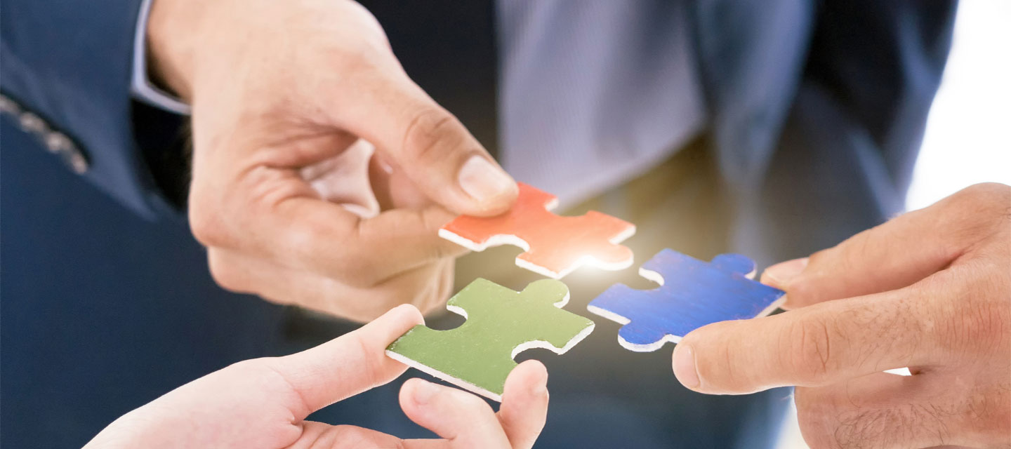 three hands holding different colored puzzle pieces to see if they fit together; management and organizational behavior MS program