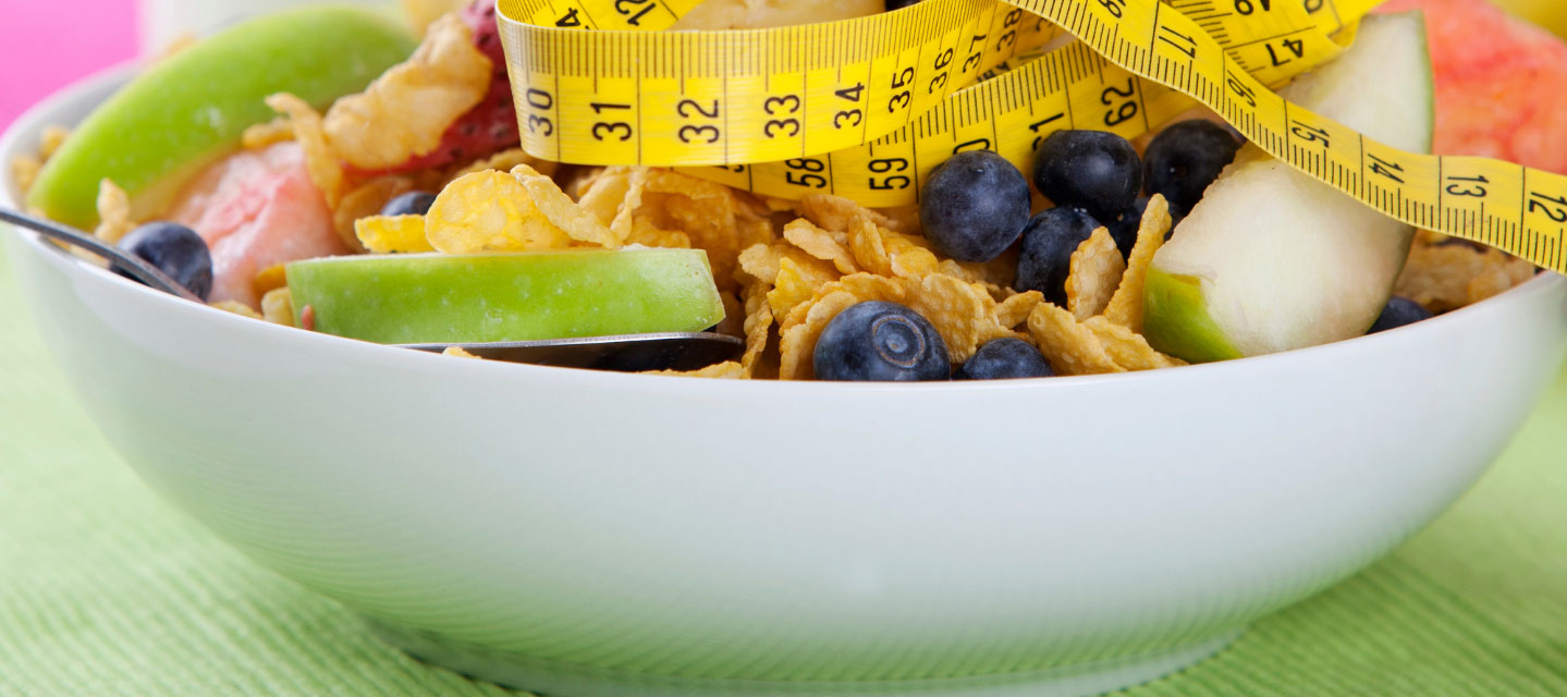 bowl of cereal with fruit and a tape measure on top; nutrition and dietetics