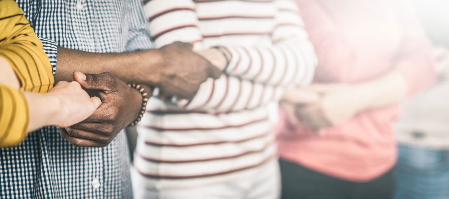 image of people's torsos crossing their arms and holding the hands of the people next to them; sociology