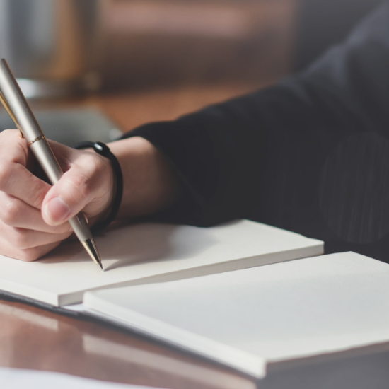 handing holding pen writing in notebook; writing and publishing program