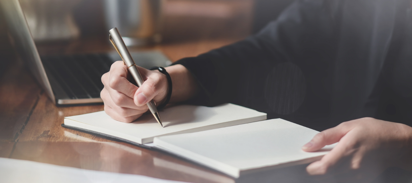handing holding pen writing in notebook; writing and publishing program