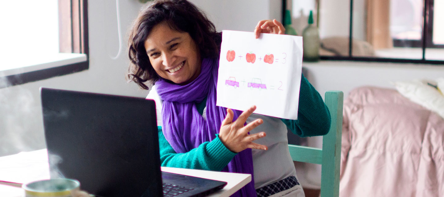 Female student holding up a chart to her computer screen for online communication