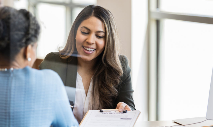 two female professionals looking at information on a clipboard; finance