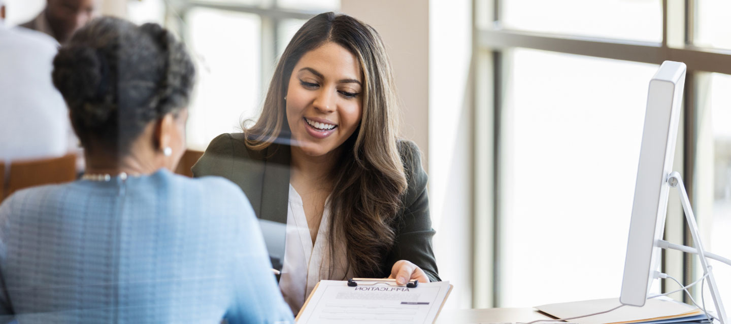 two female professionals looking at information on a clipboard; finance