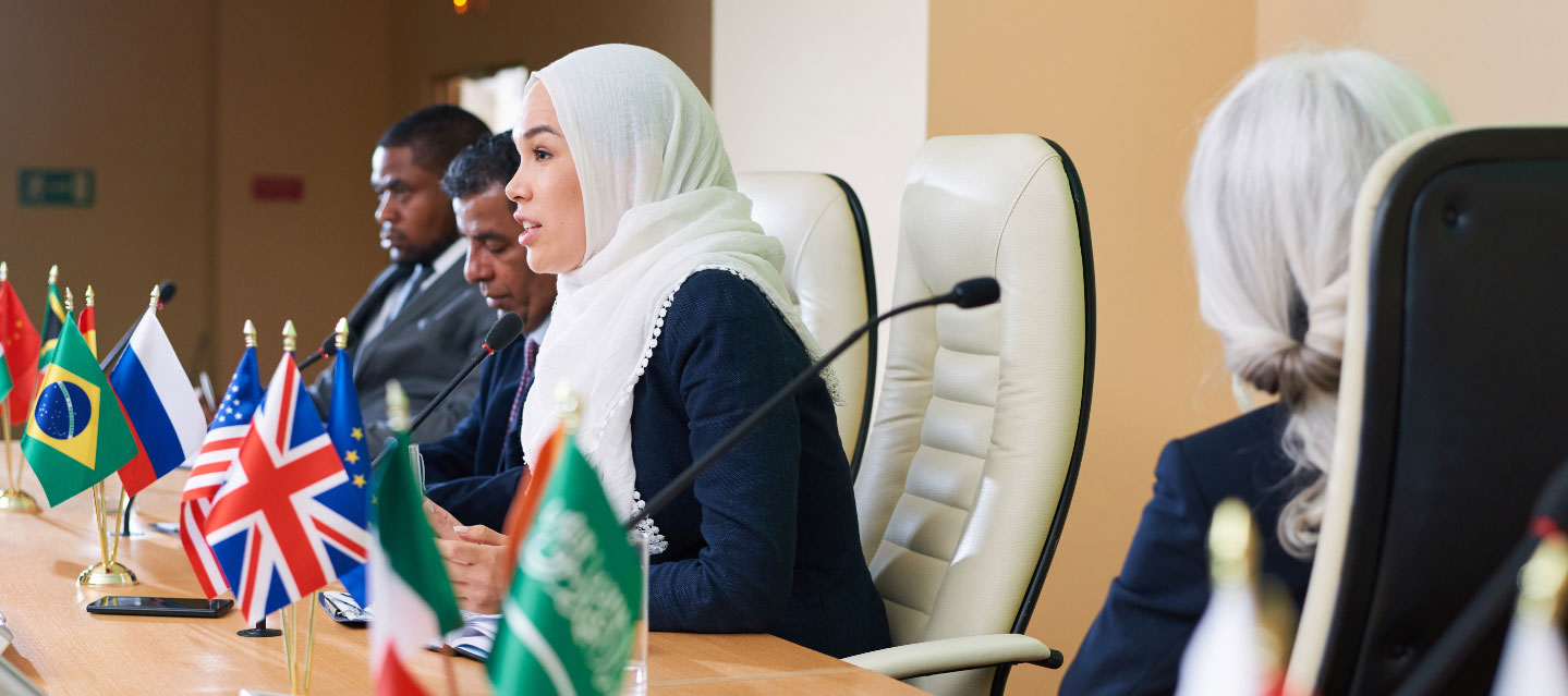 student sitting at a table with nations' flags in front of them during a model UN conference; political science