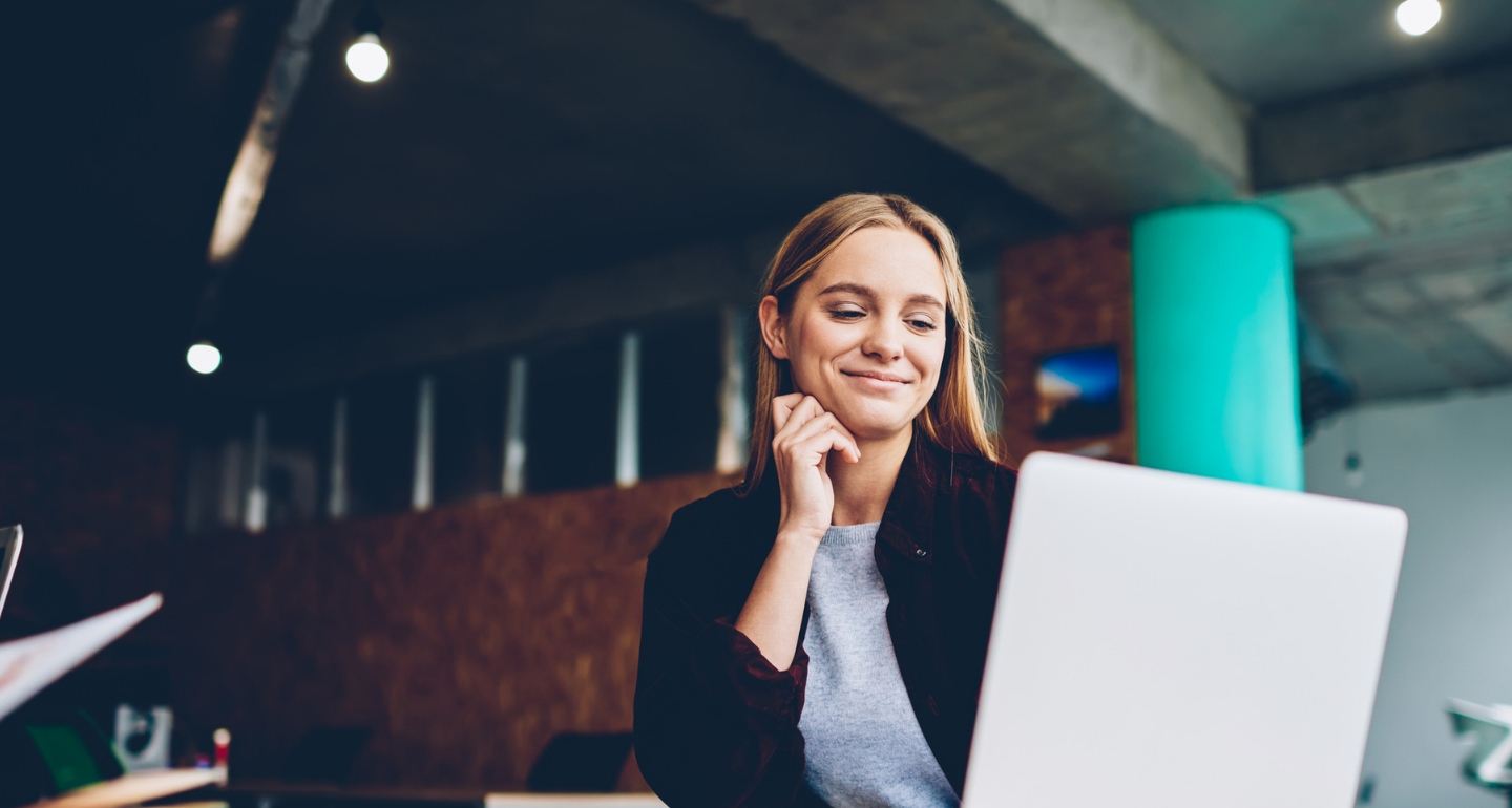 female professional smiling at computer at her desk; business analytics
