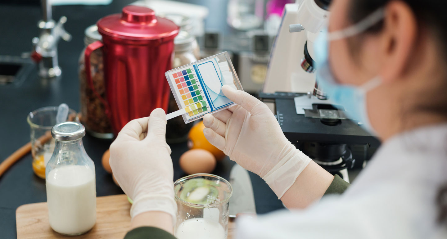 lab student comparing litmus testing results to a chart; health education and promotion