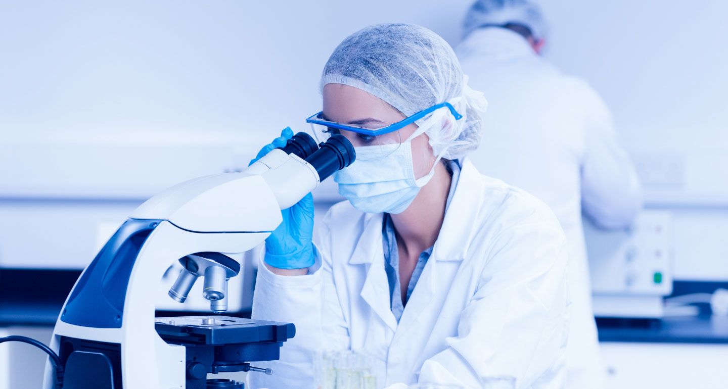 women in lab coat looking into microscope; nutrition and food sciences minor