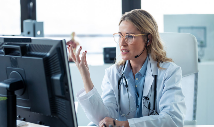 female medical professional with stethoscope at her computer engaged in a conversation online; Public Health program