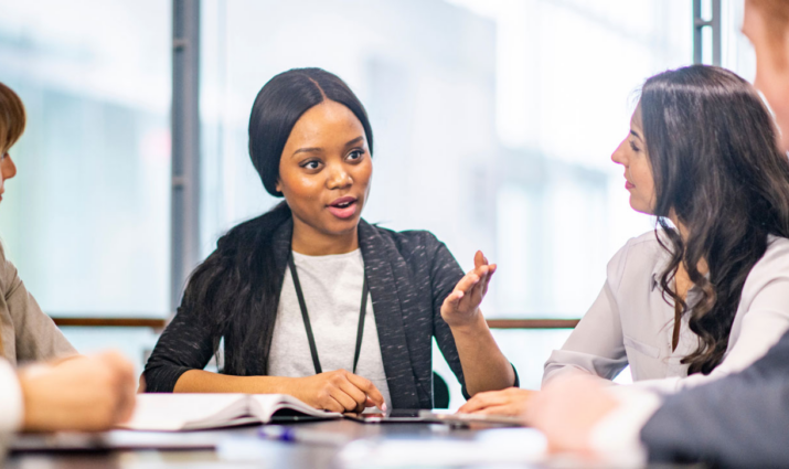 female student talking with a group of students at a table; values driven leadership