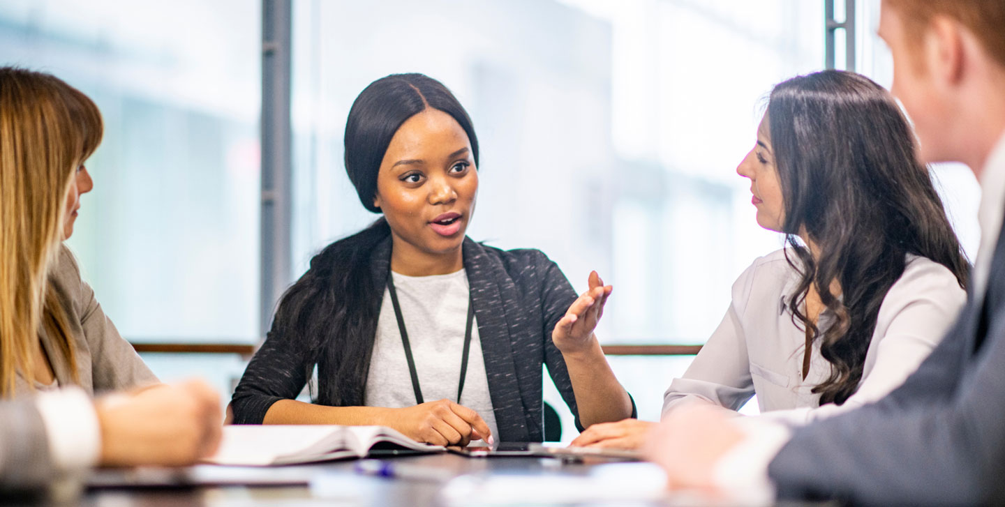 female student talking with a group of students at a table; values driven leadership