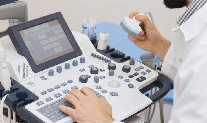 Cropped close up of a bearded male doctor operating ultrasound scanner at the clinic technology profession occupation job device medicine medical science research diagnosis sonogram sonography modern