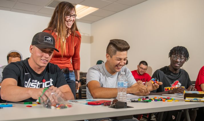 Male students interacting with a professor in a classroom