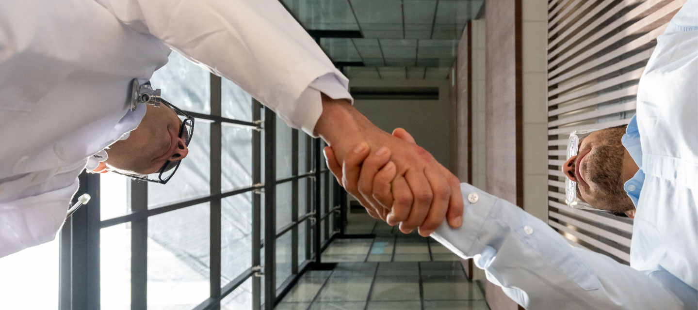 two medical professionals shaking hands, image is looking up from the floor at their hands; MS in Nursing
