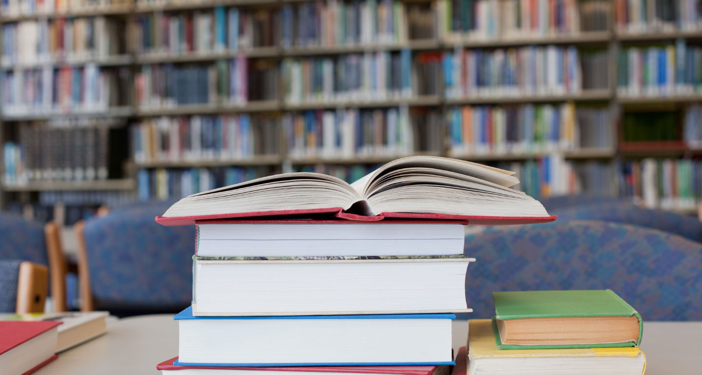 stack of books with the top book open on the top