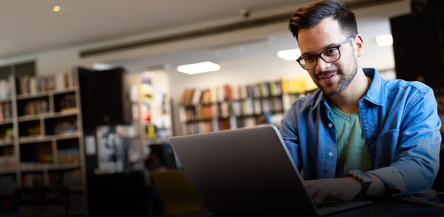male student working on laptop in a library