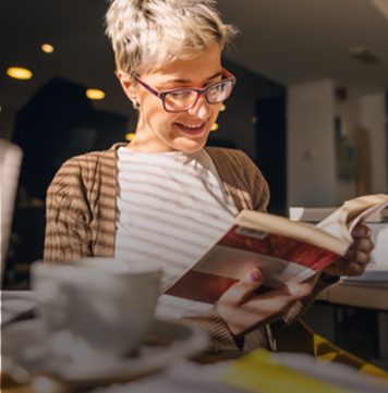 Female student smiling while looking down at an open book