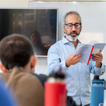 Teacher reading from book at the front of class - faculty resources - library